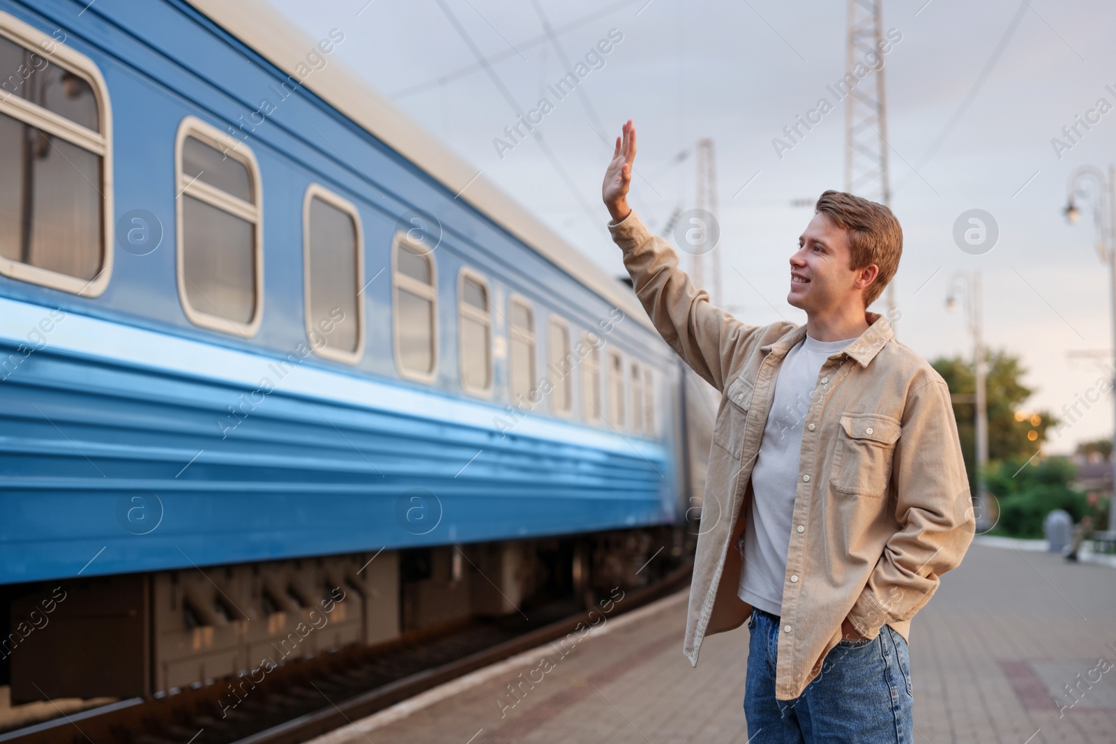 Goodbye. Happy man waving near train outdoors Photo of Goodbye. Happy man waving near train outdoors