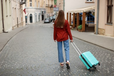 Photo of Goodbye. Woman with luggage walking outdoors, back view. Space for text