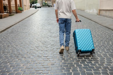 Photo of Goodbye. Man with luggage walking on city street, closeup. Space for text
