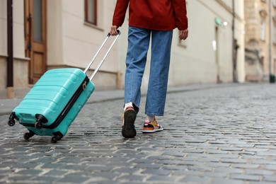 Photo of Goodbye. Woman with luggage walking on city street, closeup. Space for text
