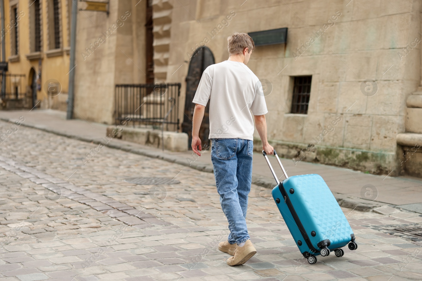 Goodbye. Man with luggage walking outdoors, back view. Space for text Photo of Goodbye. Man with luggage walking outdoors, back view. Space for text