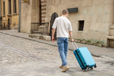 Photo of Goodbye. Man with luggage walking outdoors, back view. Space for text