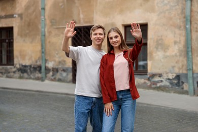 Photo of Goodbye. Lovely couple waving on city street, space for text