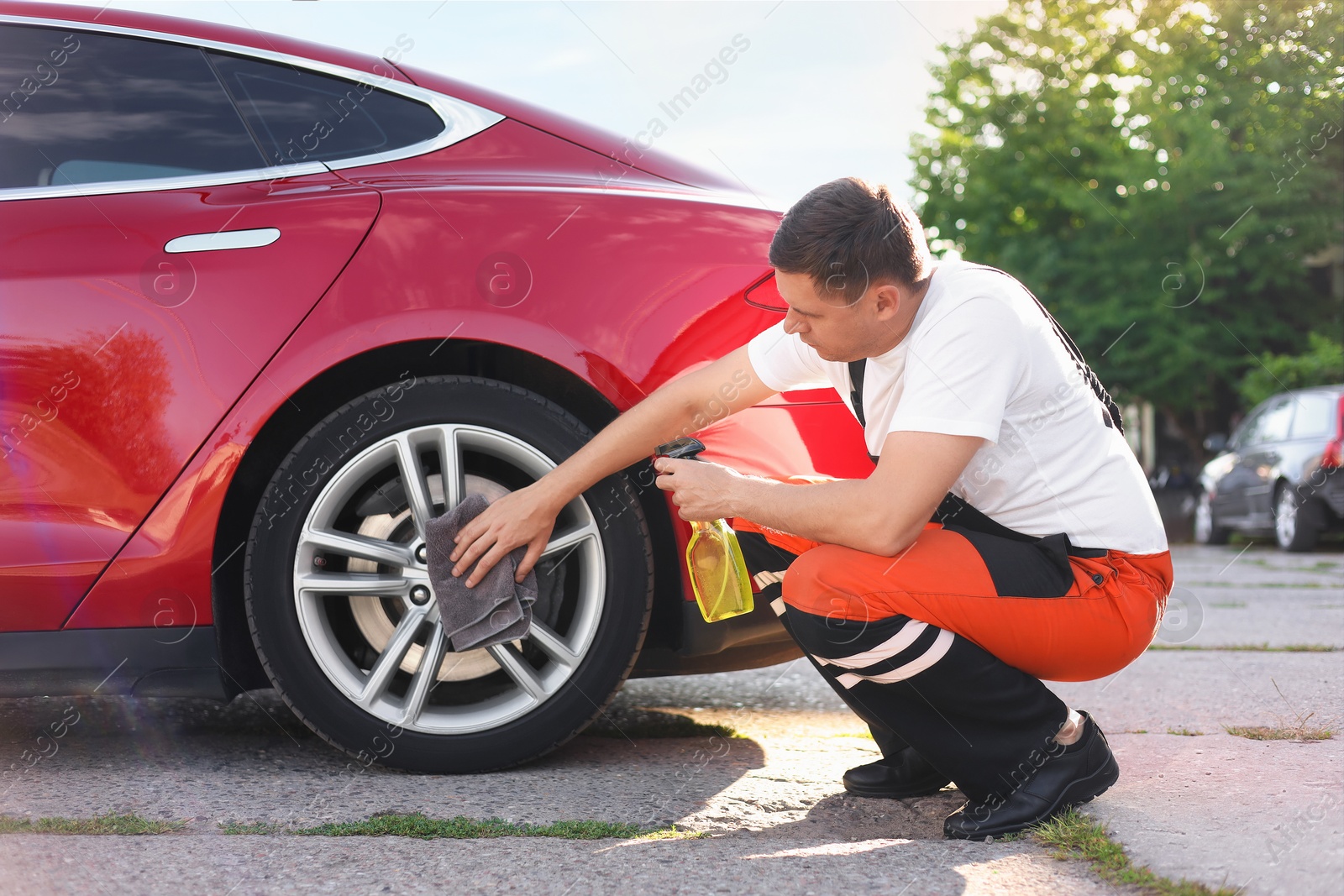 Man wiping car wheel with grey microfiber rag outdoors Photo of Man wiping car wheel with grey microfiber rag outdoors