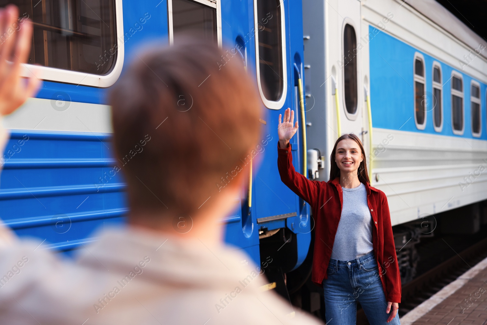 Photo of Goodbye. Man waving to his girlfriend near train outdoors, selective focus