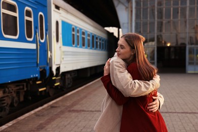 Photo of Goodbye. Lovely couple hugging near train outdoors, space for text