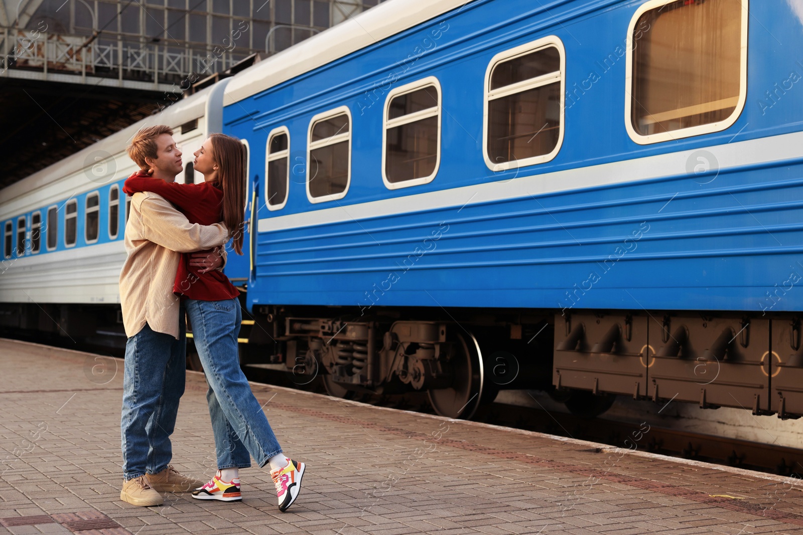 Photo of Goodbye. Lovely couple hugging near train outdoors, space for text