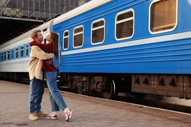 Photo of Goodbye. Lovely couple hugging near train outdoors, space for text