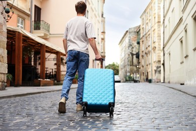 Photo of Goodbye. Man with luggage walking on city street, back view. Space for text