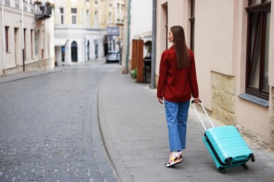 Photo of Goodbye. Woman with luggage walking outdoors, back view. Space for text