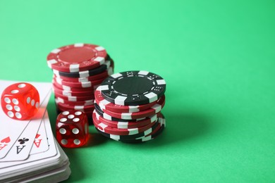 Photo of Poker chips, cards and dice on green background, space for text