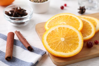 Photo of Cut orange, cinnamon sticks and cranberries on table. Mulled wine ingredients