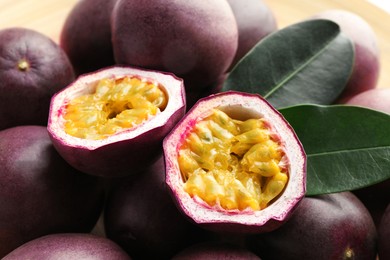 Photo of Fresh passion fruits with green leaves on table, closeup