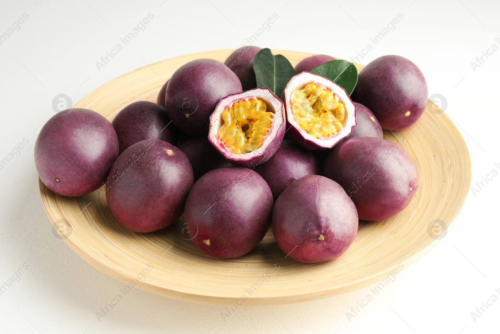 Fresh passion fruits with green leaves on white table Photo of Fresh passion fruits with green leaves on white table