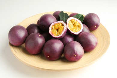 Photo of Fresh passion fruits with green leaves on white table