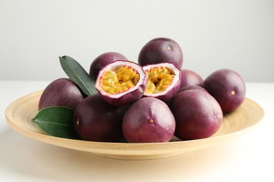 Photo of Fresh passion fruits with green leaves on white table