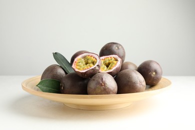 Photo of Fresh passion fruits with green leaves on white table