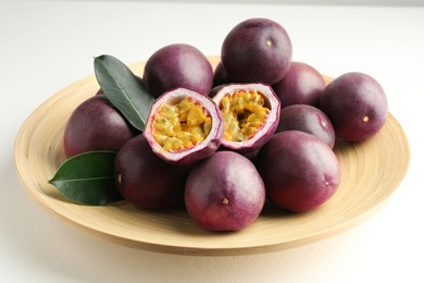 Photo of Fresh passion fruits with green leaves on white table