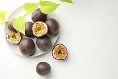 Photo of Fresh passion fruits with green leaves on white table, flat lay. Space for text