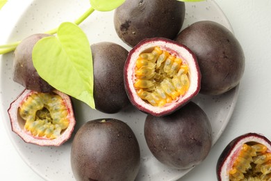 Photo of Fresh passion fruits with green leaves on white table, above view