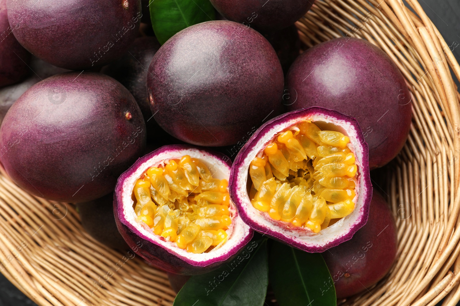 Fresh passion fruits with green leaves in wicker basket, above view Photo of Fresh passion fruits with green leaves in wicker basket, above view