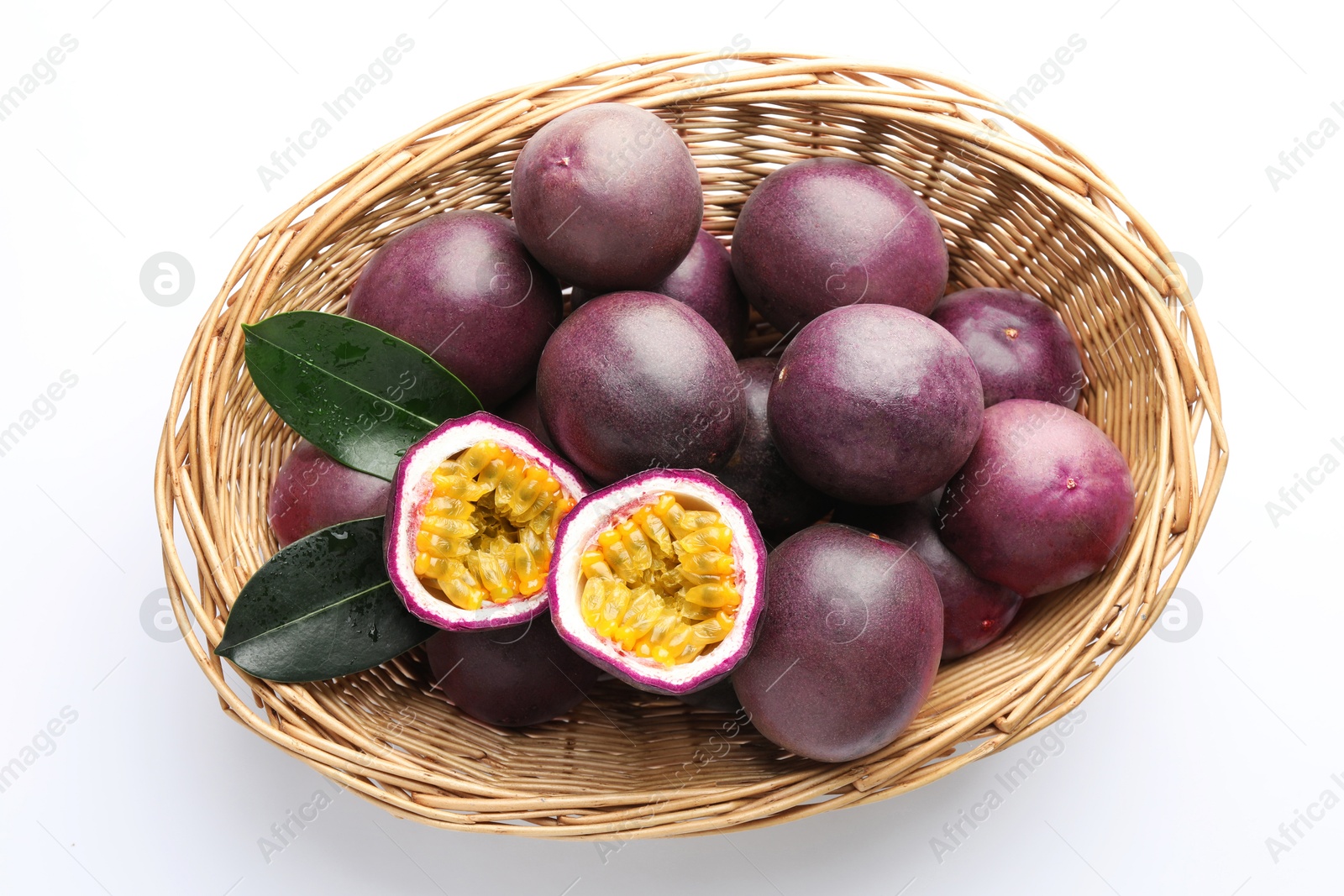 Fresh passion fruits with green leaves in wicker basket on white background, top view Photo of Fresh passion fruits with green leaves in wicker basket on white background, top view