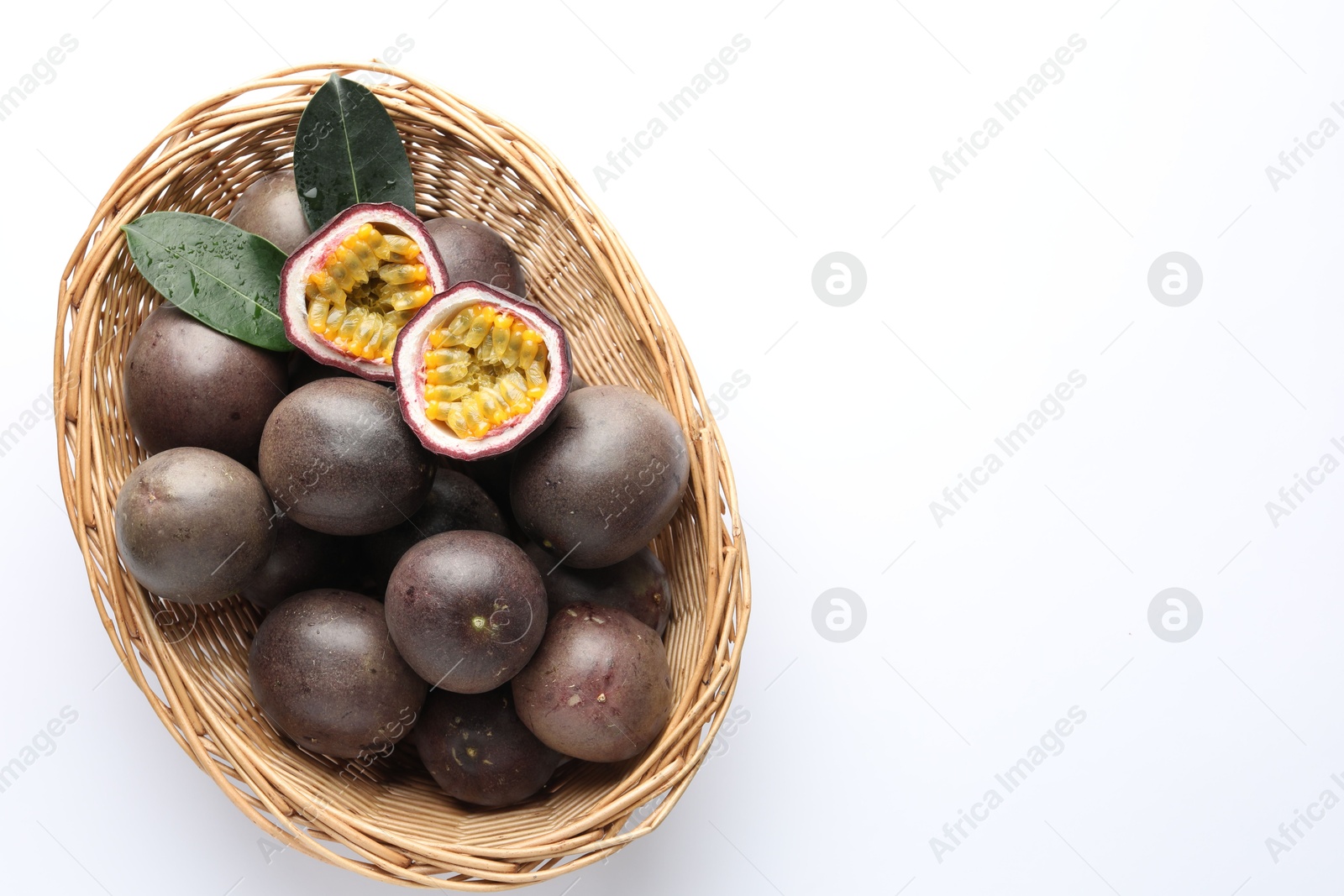 Fresh passion fruits with green leaves in wicker basket on white background, top view. Space for text Photo of Fresh passion fruits with green leaves in wicker basket on white background, top view. Space for text