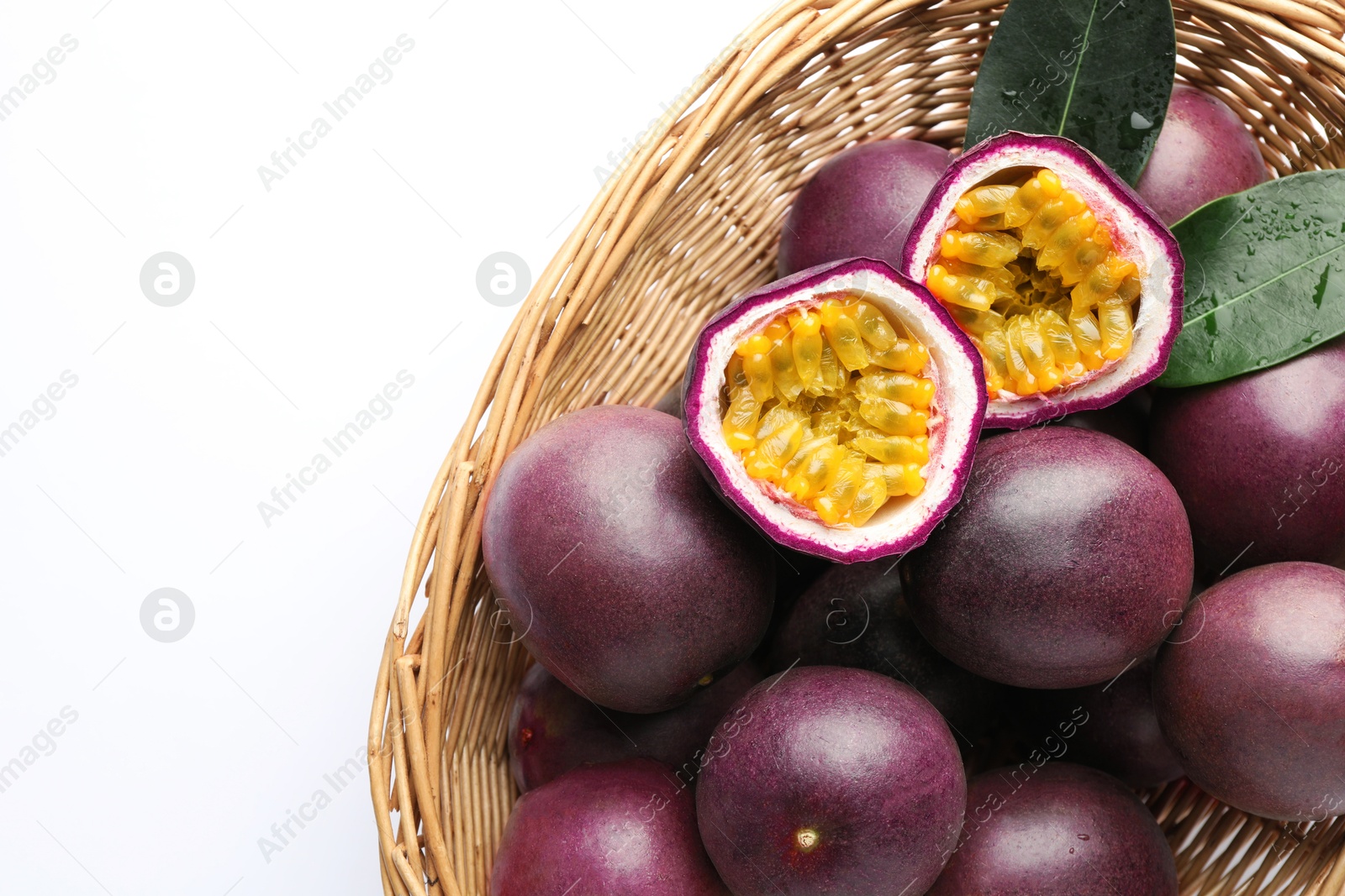 Fresh passion fruits with green leaves in wicker basket on white background, above view. Space for text Photo of Fresh passion fruits with green leaves in wicker basket on white background, above view. Space for text