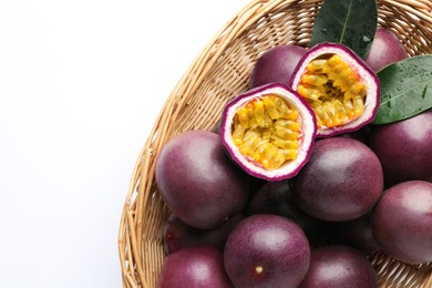 Photo of Fresh passion fruits with green leaves in wicker basket on white background, above view. Space for text