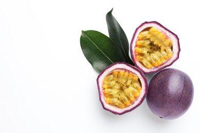 Photo of Fresh passion fruits with green leaves on white background, top view. Space for text