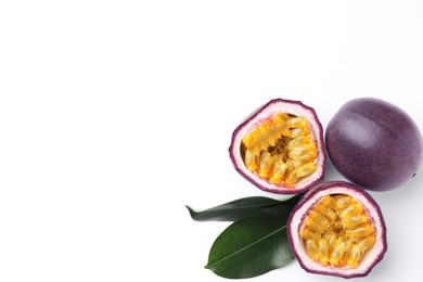 Photo of Fresh passion fruits with green leaves on white background, flat lay. Space for text