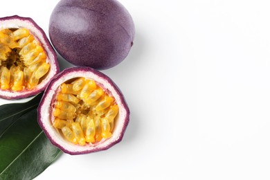 Photo of Fresh passion fruits with green leaves on white background, flat lay. Space for text