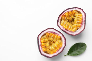 Photo of Halves of fresh passion fruit and green leaf on white background, top view. Space for text