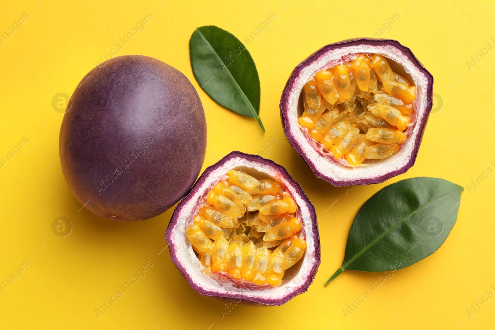 Fresh passion fruits with green leaves on yellow background, above view Photo of Fresh passion fruits with green leaves on yellow background, above view