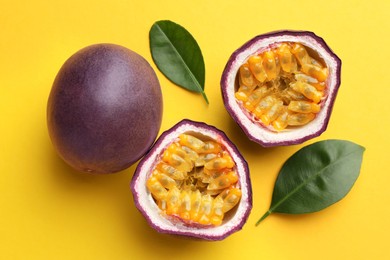 Photo of Fresh passion fruits with green leaves on yellow background, above view