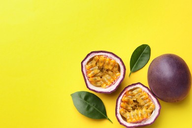 Photo of Fresh passion fruits with green leaves on yellow background, flat lay. Space for text