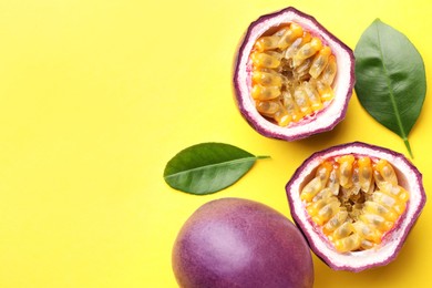 Photo of Fresh passion fruits with green leaves on yellow background, flat lay. Space for text