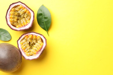 Photo of Fresh passion fruits with green leaves on yellow background, flat lay. Space for text