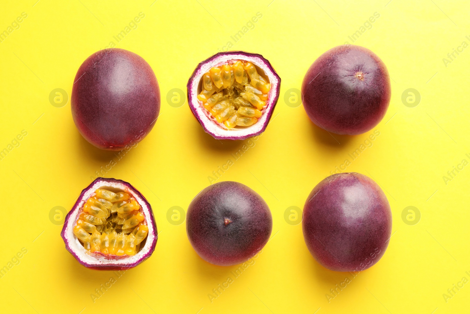 Fresh passion fruits on yellow background, flat lay. Whole and cut Photo of Fresh passion fruits on yellow background, flat lay. Whole and cut