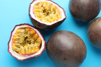 Photo of Fresh passion fruits on light blue background, closeup. Whole and cut