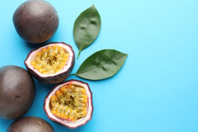 Photo of Fresh passion fruits with green leaves on light blue background, above view. Space for text