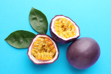 Photo of Fresh passion fruits with green leaves on light blue background, above view