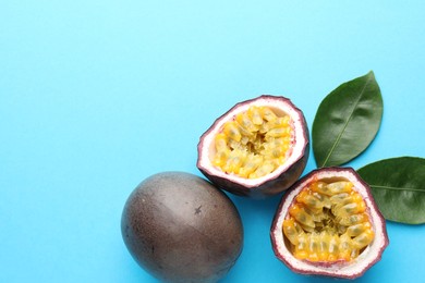 Photo of Fresh passion fruits with green leaves on light blue background, above view. Space for text