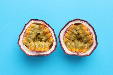 Photo of Halves of fresh passion fruit on light blue background, closeup
