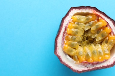 Photo of Half of fresh passion fruit on light blue background, closeup. Space for text