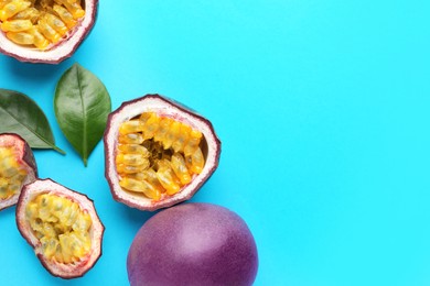 Photo of Fresh passion fruits with green leaves on light blue background, flat lay. Space for text