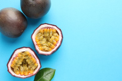 Photo of Fresh passion fruits with green leaf on light blue background, flat lay. Space for text