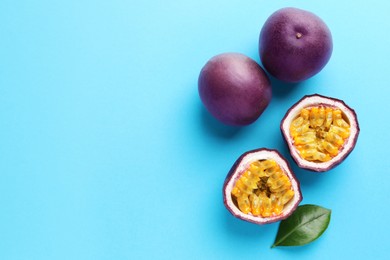 Photo of Fresh passion fruits with green leaf on light blue background, flat lay. Space for text