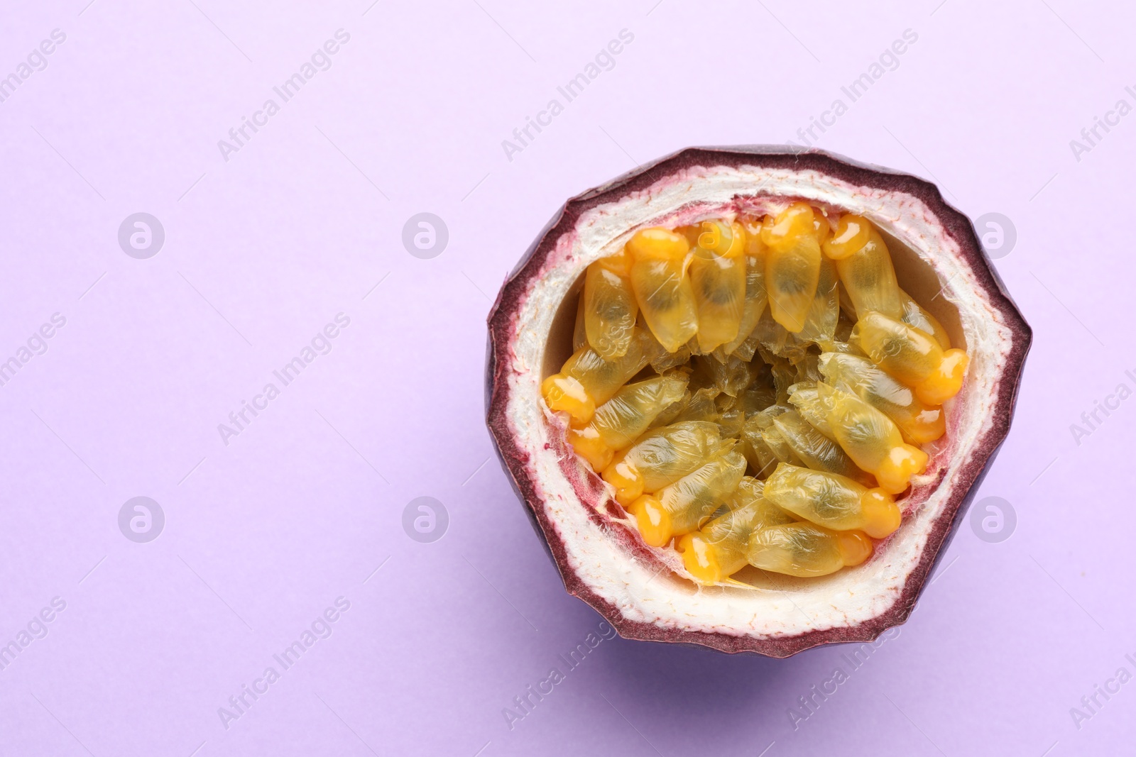 Half of fresh passion fruit on violet background, closeup. Space for text Photo of Half of fresh passion fruit on violet background, closeup. Space for text