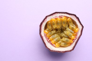 Photo of Half of fresh passion fruit on violet background, closeup. Space for text